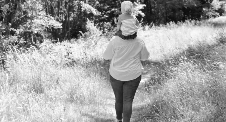 Sabina Patot marche en forêt avec son fils sur les épaules.